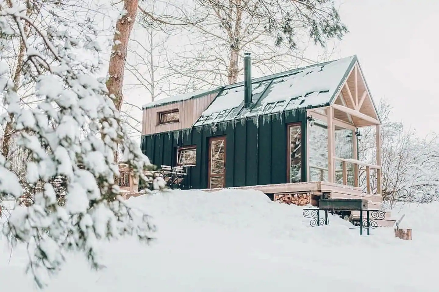 Une petite maison en bois clair dans la neige au milieu des arbres