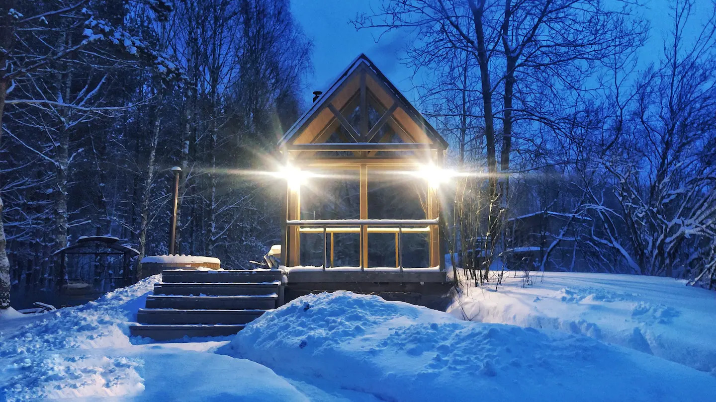 Une petite maison en bois clair dans la neige au milieu des arbres