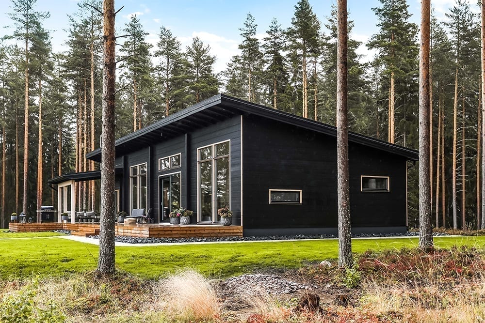 Une maison intemporelle en bois et noire dans un environnement forestier