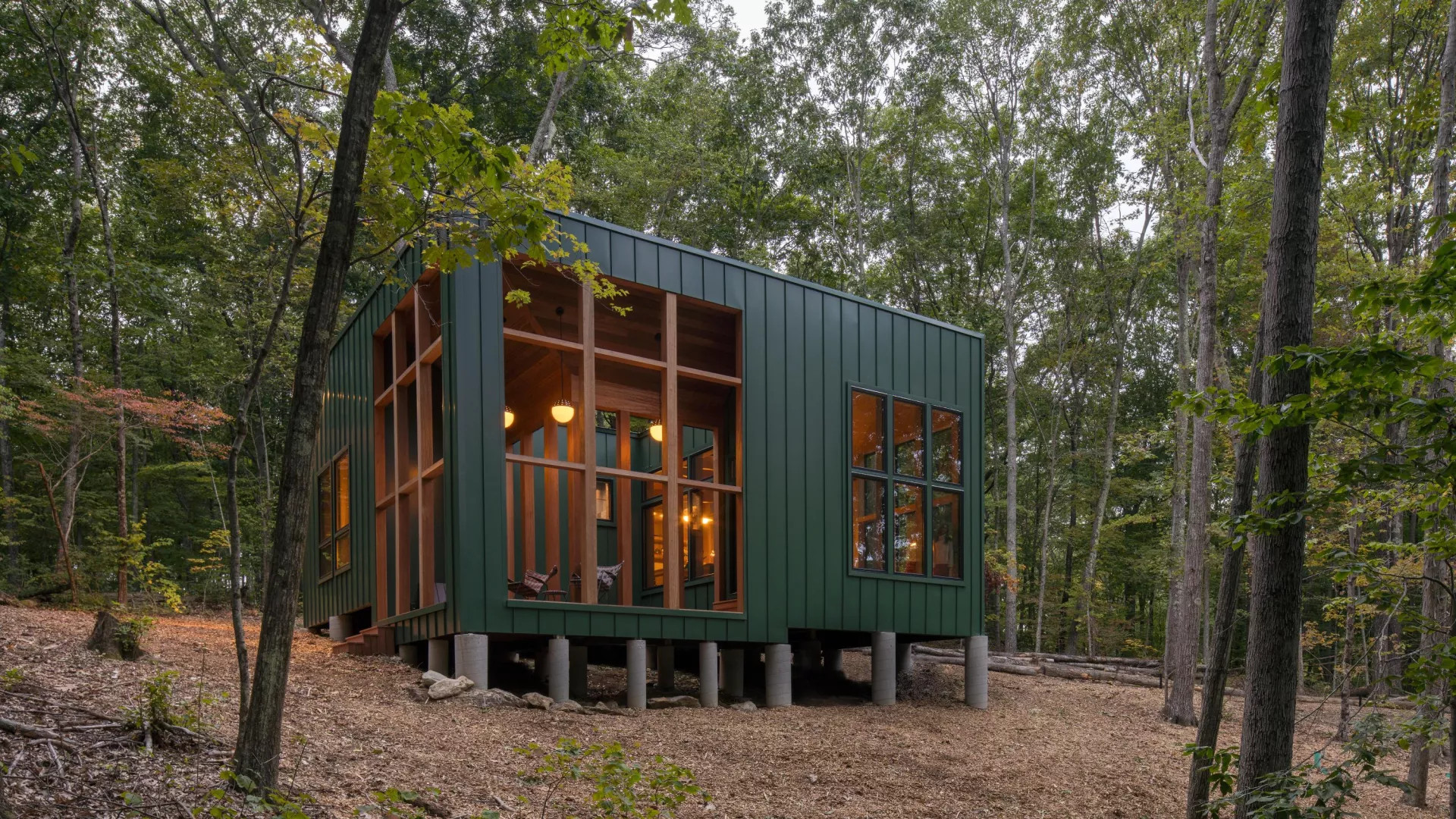 maison en bois cubique sur pilotis façade verte