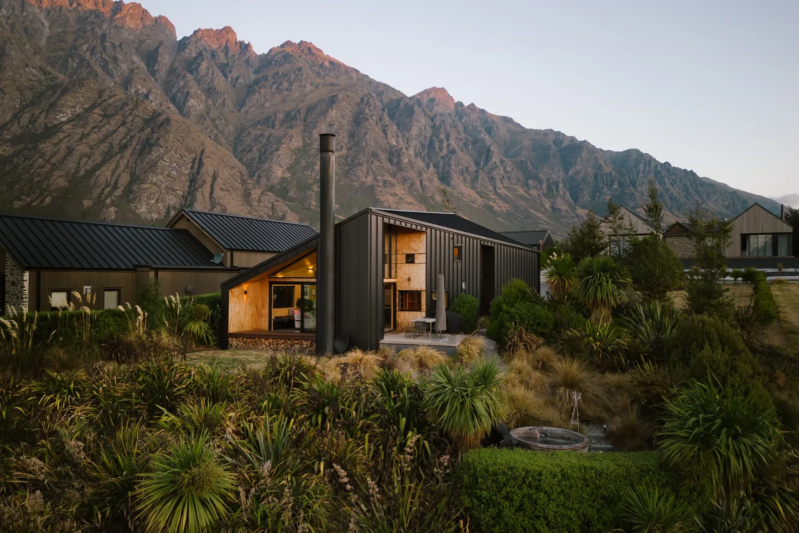 A black and geometric home surrounded by New Zealand nature